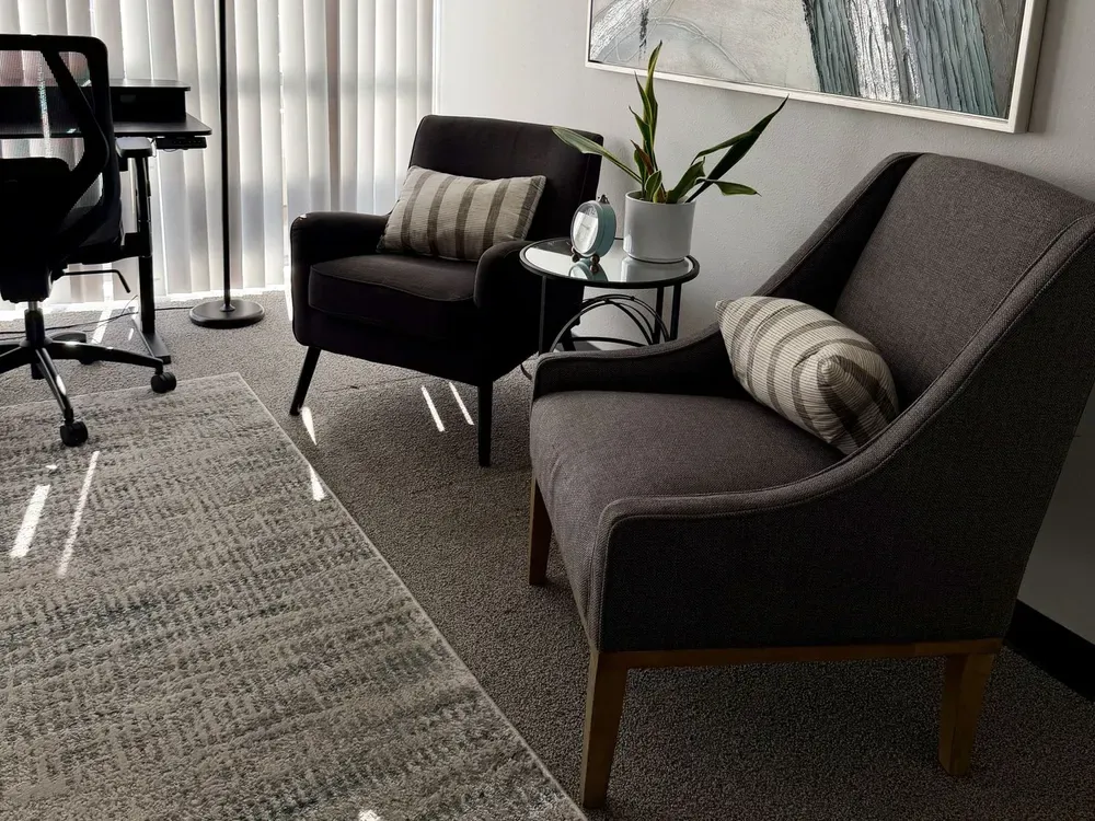 Anaheim Hills office therapy room: two armchairs with striped cushions, a small round table and a plant.